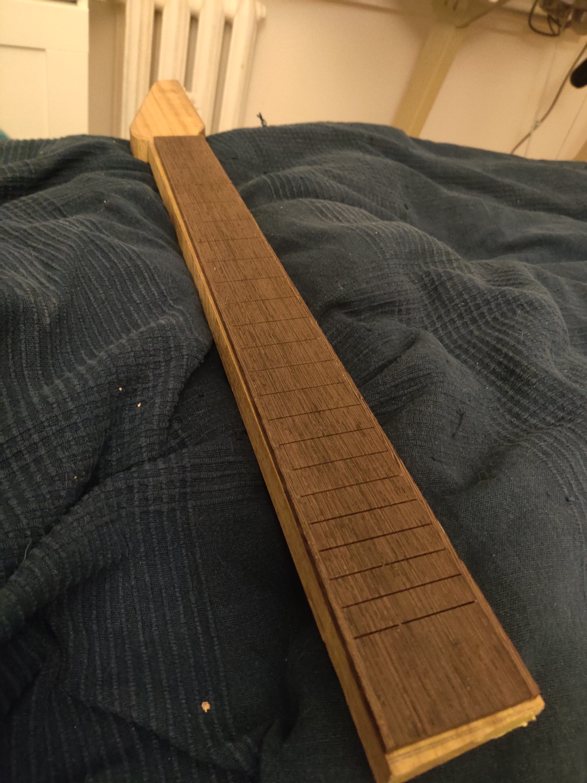 A roughly cut guitar neck with fretboard on top